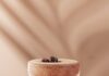 Frozen Tiki-Style Espresso Martini A short cocktail glass with a frozen Espresso Martini with three coffee beans on top on a pink background.