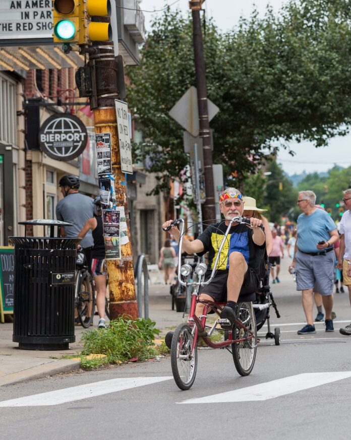 People riding bikes and walking in the streets of Pittsburgh in front of Row House in Lawrenceville.
