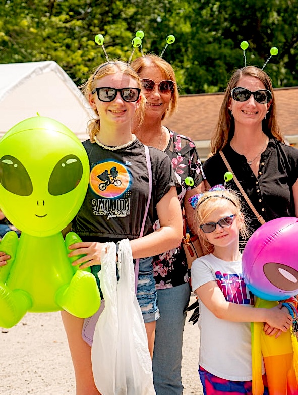 The Truth Is Out There. And So Is the Kecksburg UFO Festival Near Pittsburgh A family stands with alien ears on their heads, holding blow up aliens.