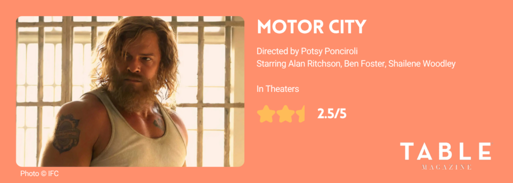 An orange rating card for Motor City with a 2.5/5 star rating and a man with long hair and a beard and muscles stands in a white muscle tee. 