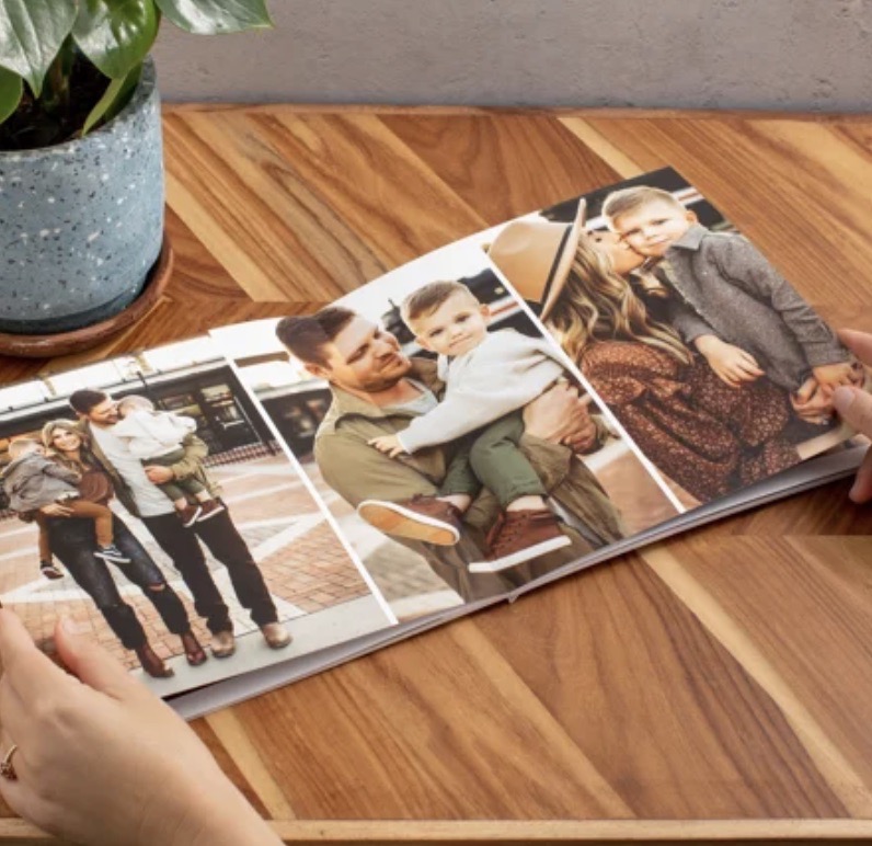 A photo book with three photos sits on a wood table.