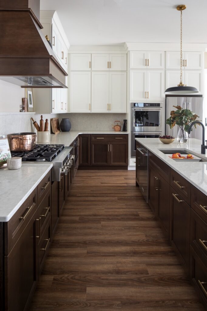A middle island counter with a sink and another marble counter against the wall with a stove and white cabinets.