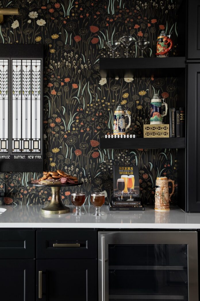 A black and wildflower wall paper over a white marble table with black shelves on the wall.