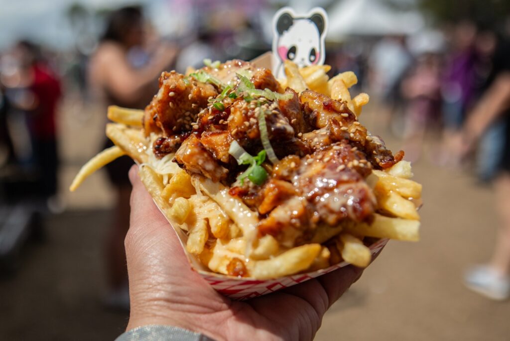 A container of fries with a curry on top and panda decoration.