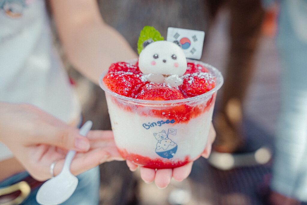 A person holds a dessert with a panda decor topping.