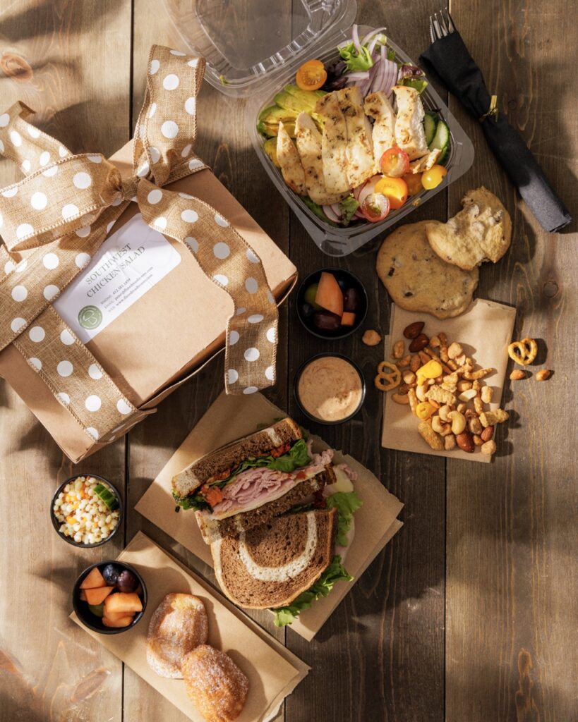 A set up of brown box lunches with sandwiches and salads.