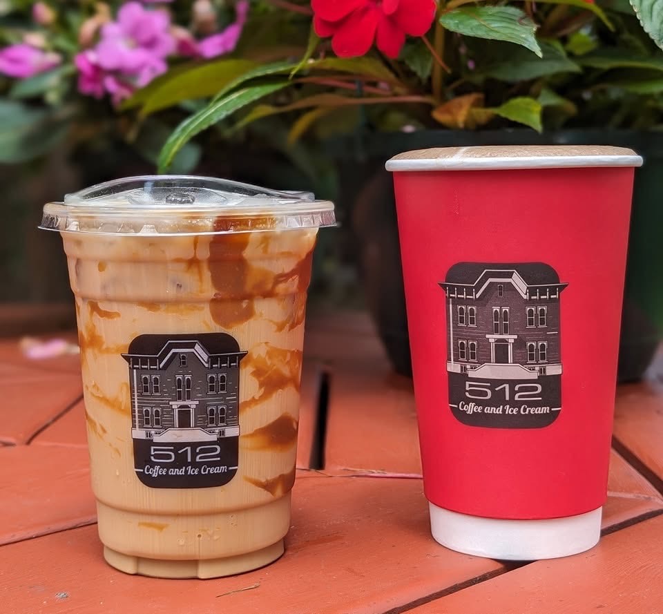 Two cups of coffee, one hot in a red to-go cup and the other in a clear iced to-go cup.