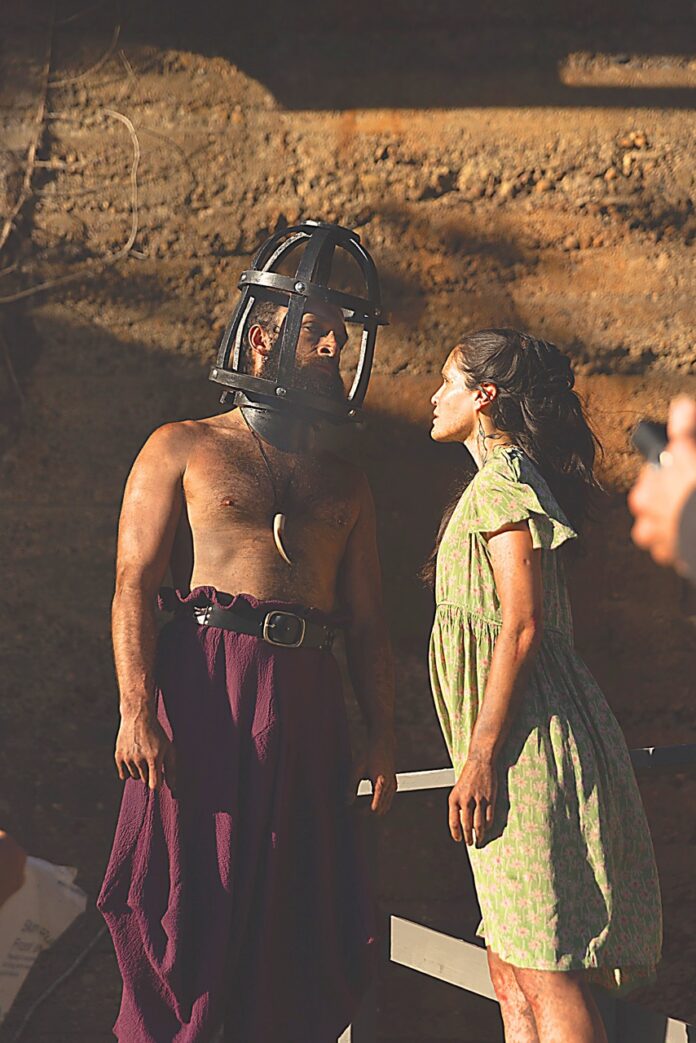 Quantum Theatre Brings Us Back to Pittsburgh’s Forgotten Island With 'The Tempest' A woman in a dress looks up at a shirtless man with his head in a cage.