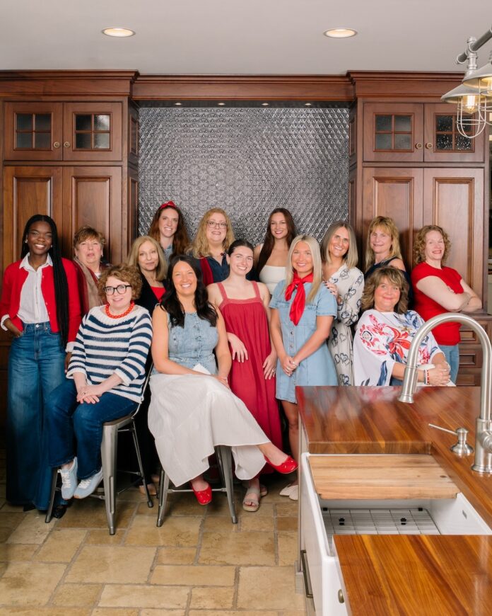 SPLASH Pittsburgh Kitchen and Bath Head of the Table TABLE Magazine A group of the women sales team at Splash in a kitchen showroom with oak cabinets and counter and silver sink.