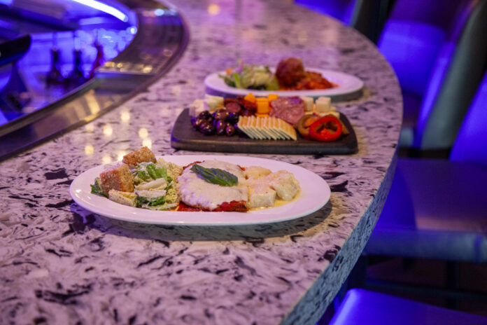 Sip and Social at Rivers Casino Pittsburgh Two plates of Italian food with a small charcuterie board between them sitting on a rounded marble counter.