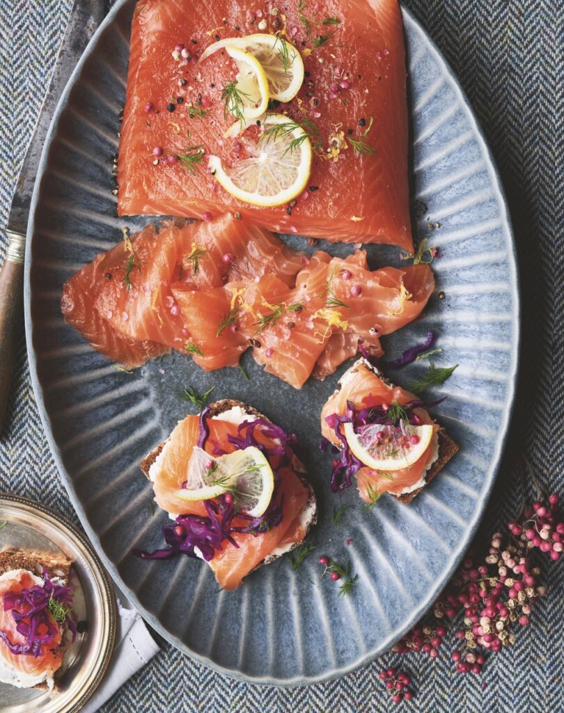 An oval plate with a spice cured salmon with lemon slices on top.