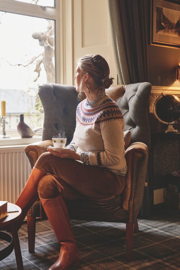 A woman sits holding sit in his crossed legged lap in an antique chair.