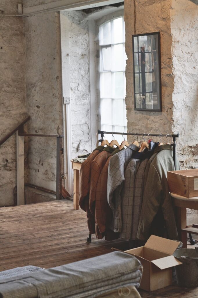 A rack of tweed clothing in a stone room.