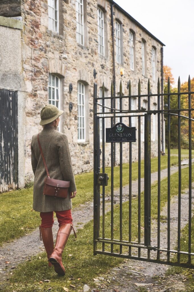 A woman walks through a gate in the Scottish Highlands.
