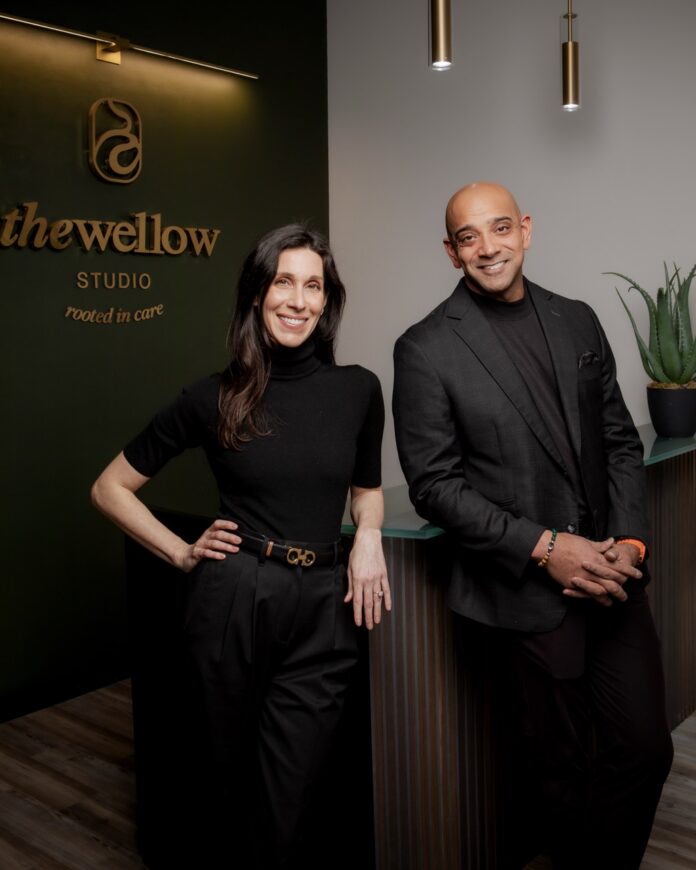 Sunjay Mannan and Sophia Moses stand together at the front desk of The Wellow in black clothing.