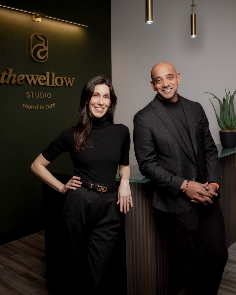 Sunjay Mannan and Sophia Moses stand together at the front desk of The Wellow in black clothing.
