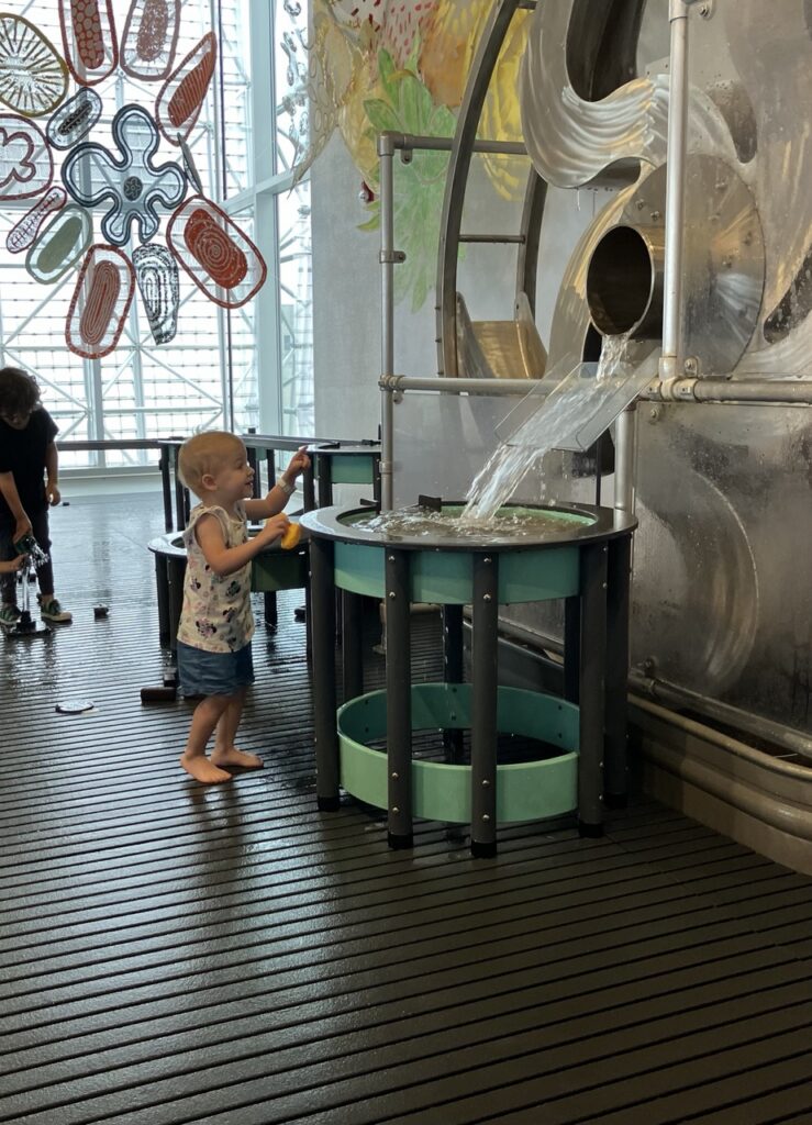 A little kid playing with a water table in Pittsburgh's Children's Museum.