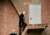 The Truth Is Out There. And So Is the Kecksburg UFO Festival Near Pittsburgh Two people in alien masks walking up a staircase on a brick building.