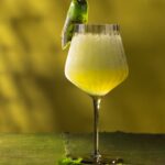 A tall stem wine glass with a frozen sauvignon blanc cocktail inside and a jalapeno pepper garnish with slices of jalapeno below the glass.