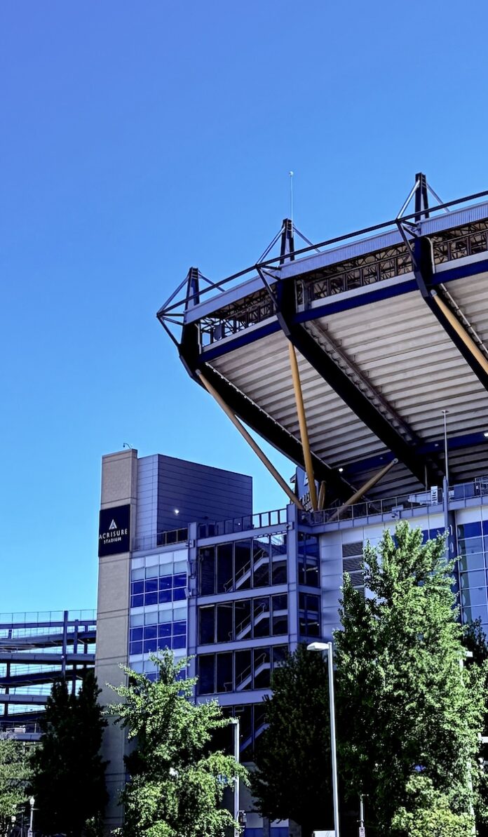 The outside of Acrisure Stadium with park of the high seats and walking tracks in front of a blue sky.