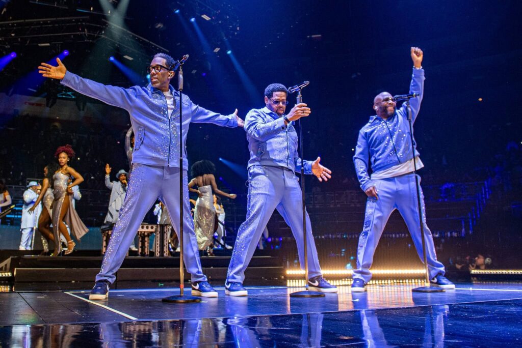 Three men in sparkly blue suits performing on stage at a Pittsburgh event