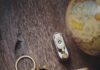 Cancer Horoscope 2026–2027: Your Yearly Astrology Forecast A gold crab keychain on top of a wood table and lather wallet beside a globe.