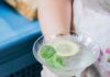 Grigio Spritz Recipe for a Light and Refreshing Summer Cocktail Woman holding a refreshing Grigio Spritz cocktail garnished with a lemon slice and fresh basil.