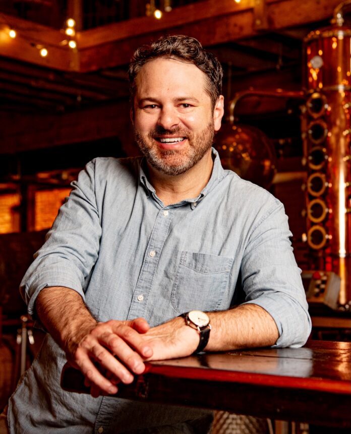 Matthew stands at a bar with his arms on the table.