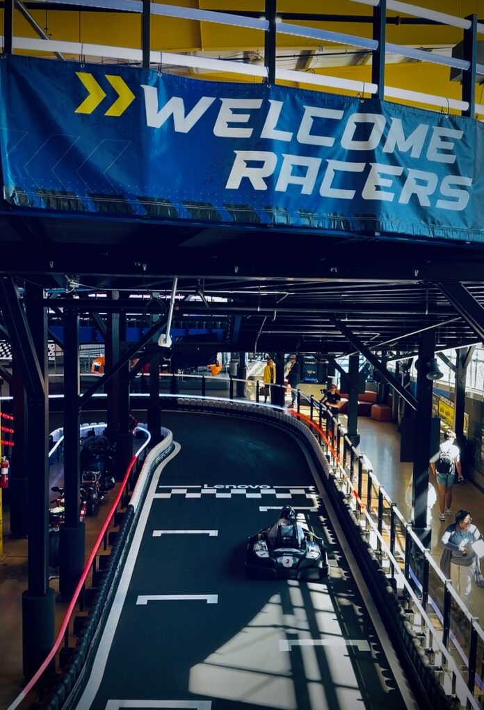 A go-kart racing track with a rider on it and a "Welcome Racers" sign above it.
