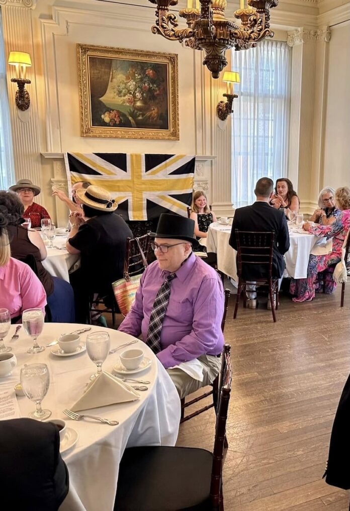 People in hats at a tea party in Pittsburgh, with Union Jack flag