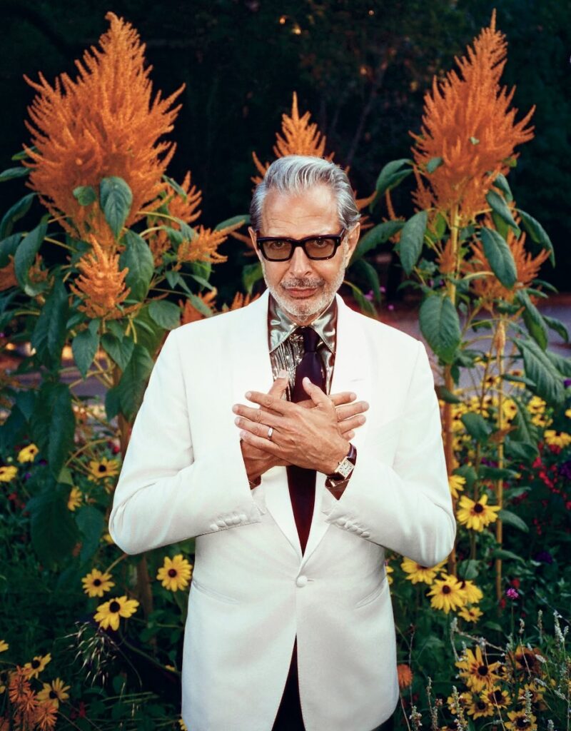 Jeff Goldblum in a white suit at a Pittsburgh event with orange flowers.