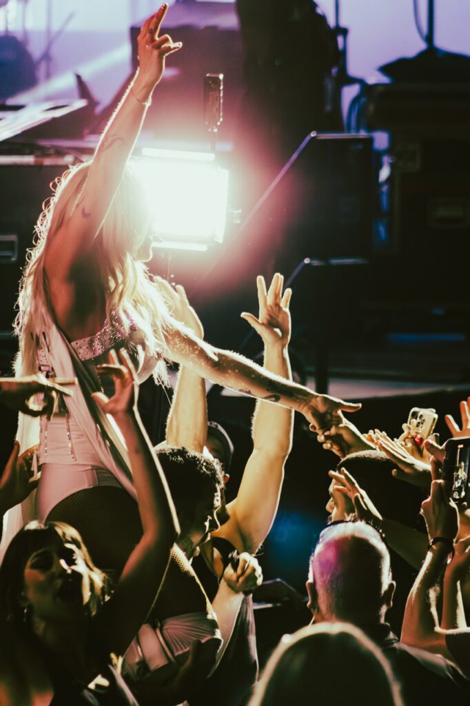 Kesha on a dancer's shoulders interacting and holding hands with the crowd.
