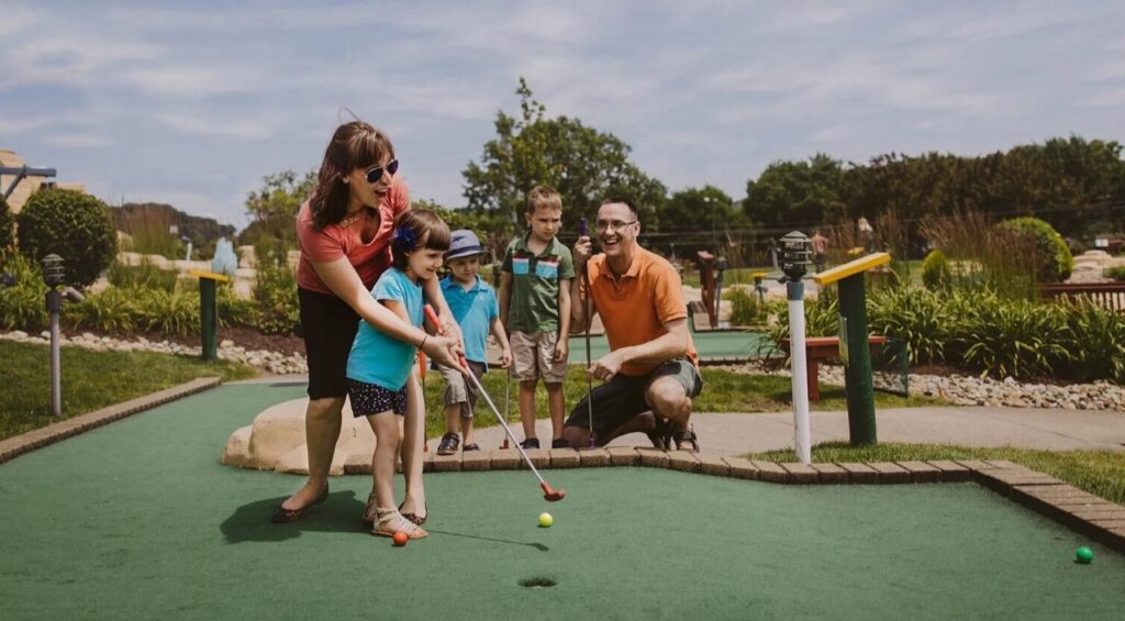A family playing mini golf on a green golf course.