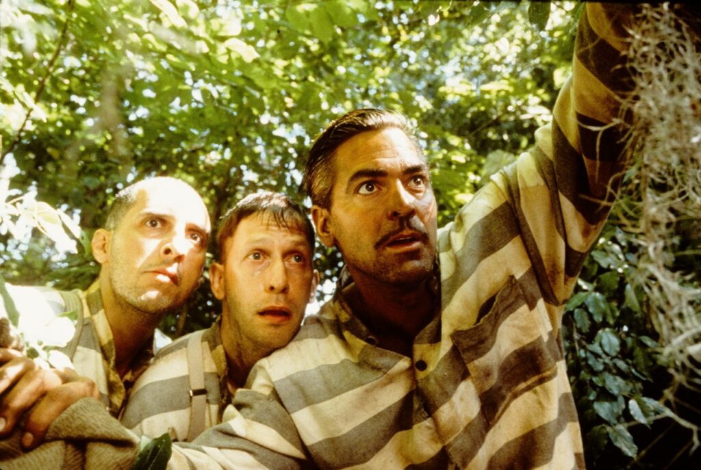 Three men in striped prison uniforms look up in surprise outdoors.