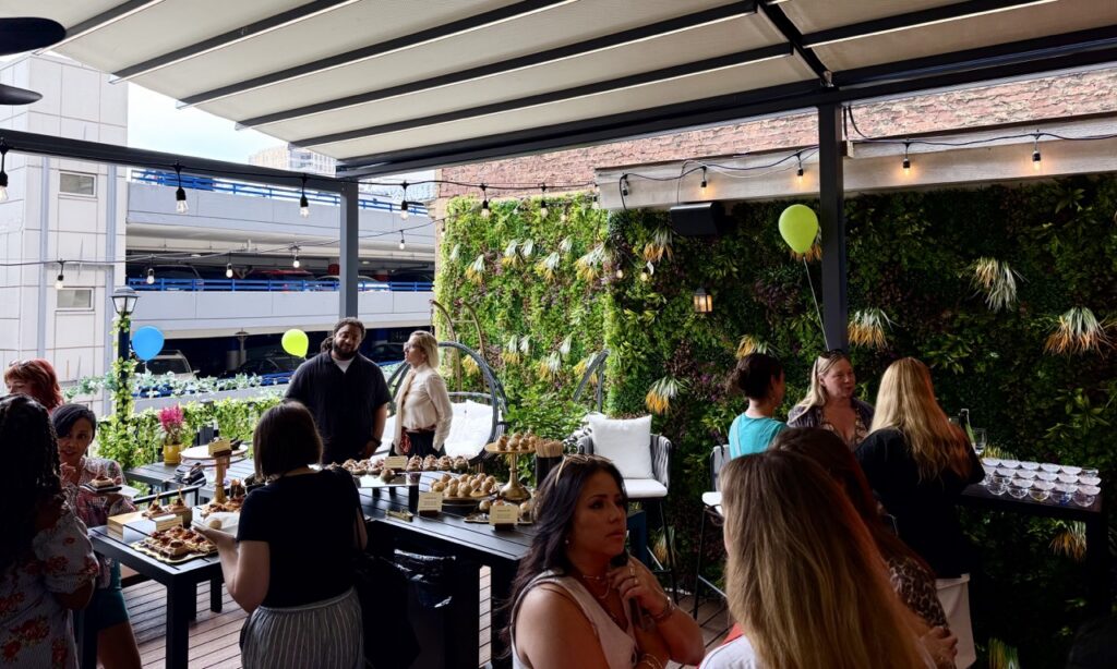 The rooftop bar and dining area of Okane with green flower walls and people throughout.