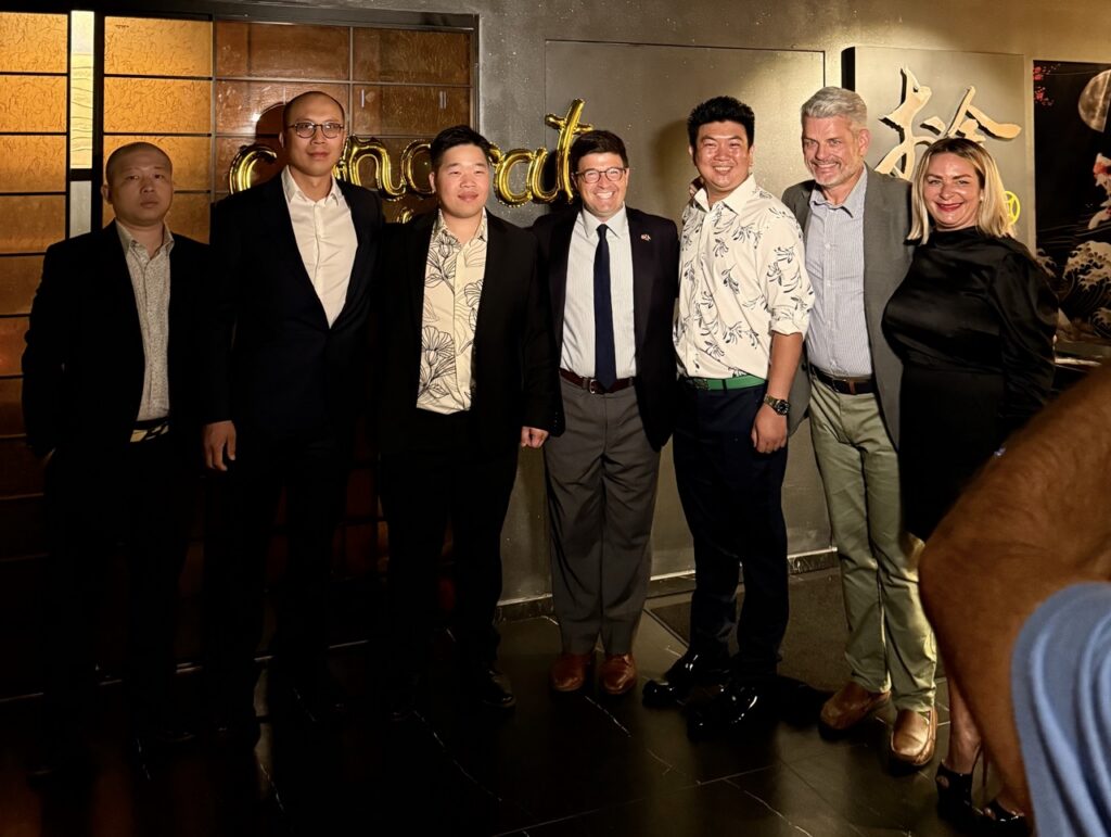 A group of people stand against a congrats wall.