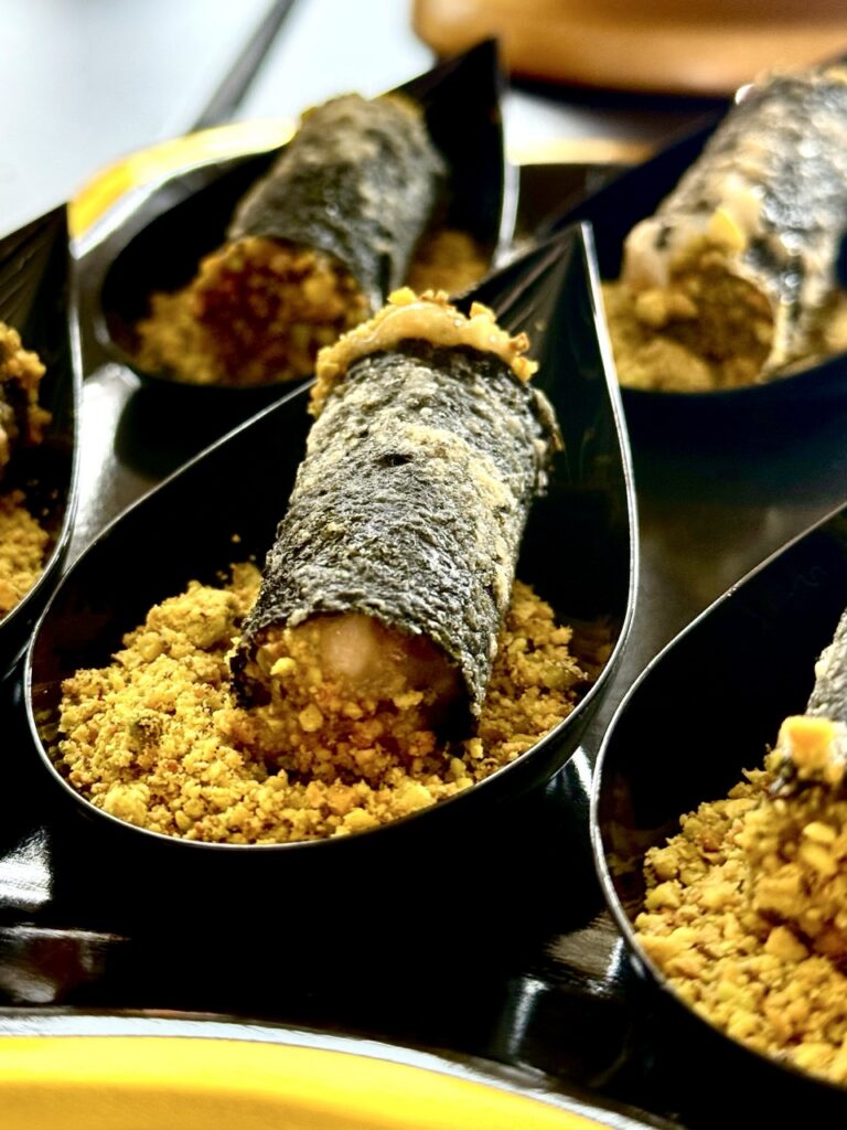 A Salmon Cigar rolled in crunch in a small droplet shaped spoon.
