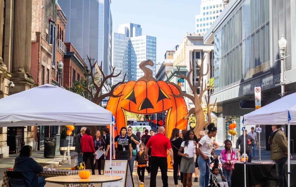 People at a fall festival with a giant pumpkin arch in Pittsburgh