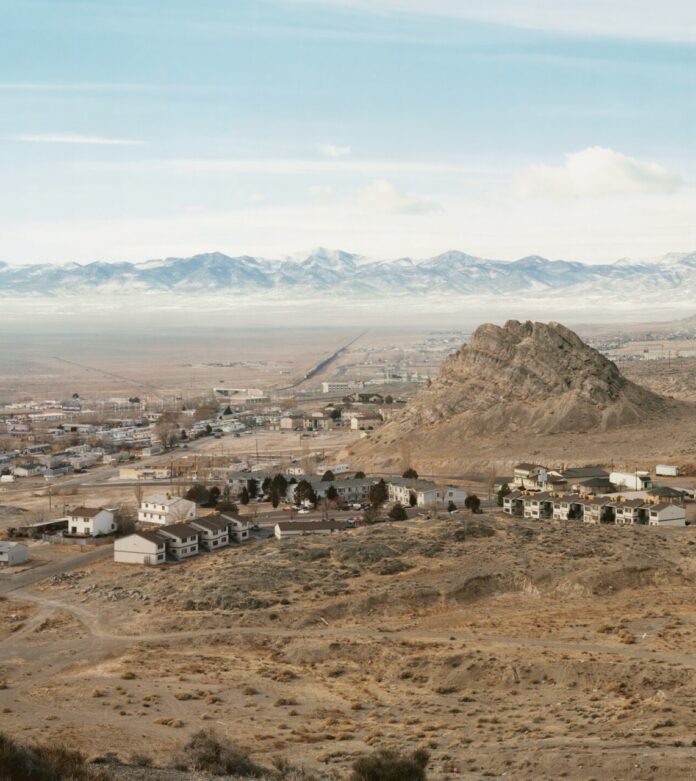 A picture of a dessert landscape with a small town center near a large mound in the dirt.