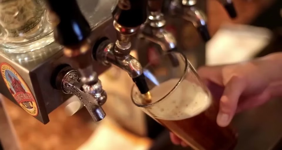A person pouring beer from a draft tap.