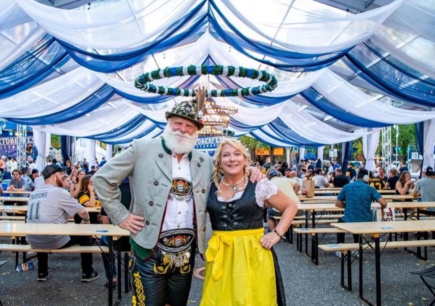 Two people under a blue and white tent in German clothing.
