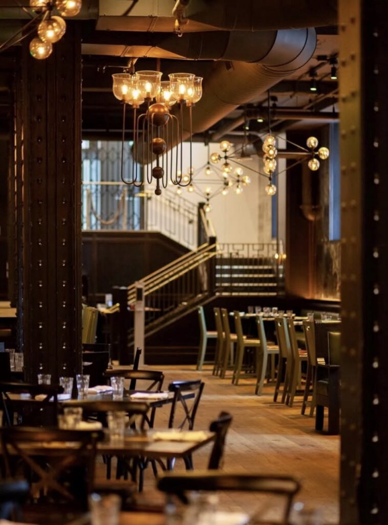 The inside of The Commoner with industrial lighting and tables.