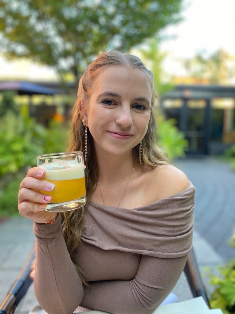 Angela Santucci Mazza sits at a table with a cocktail in her hand.