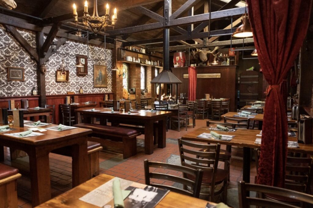 The inside of a tavern with tables along both walls.