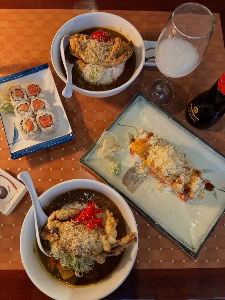 Plates of sushi on a brown table with a wine glass with a milky color drink.