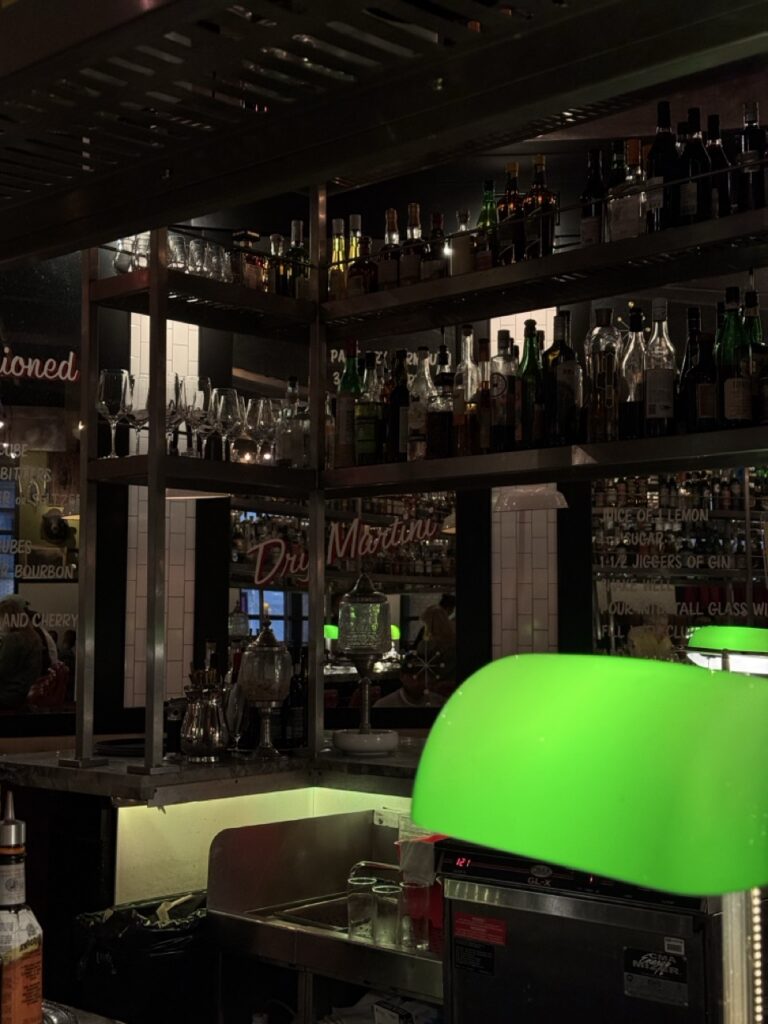 The inside of a low lit bar with shelves of bottles.