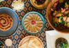 Pittsburgh Restaurant Week 2026: The Menus You Shouldn’t Miss A variety of dishes on a pattern table on various size plates and a bowl of salad.