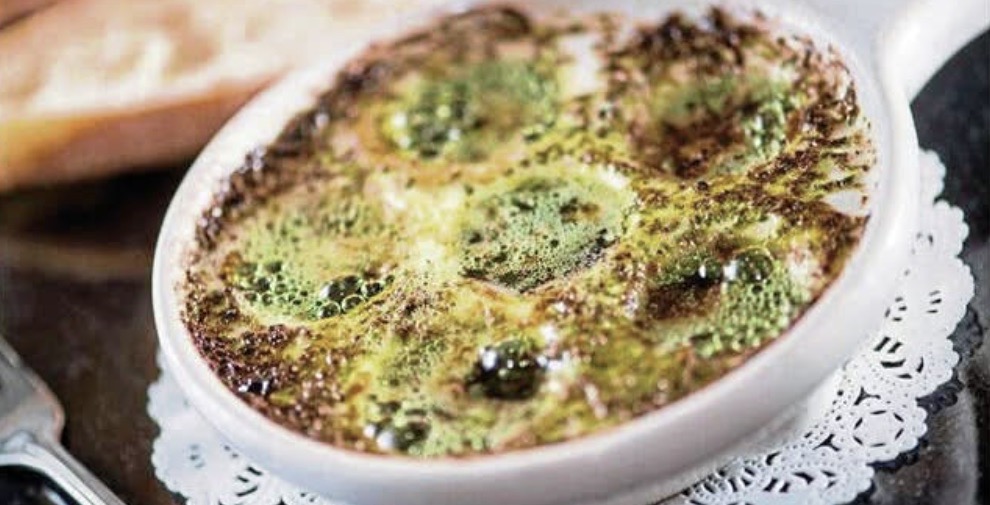 A white bowl of oysters on a table.