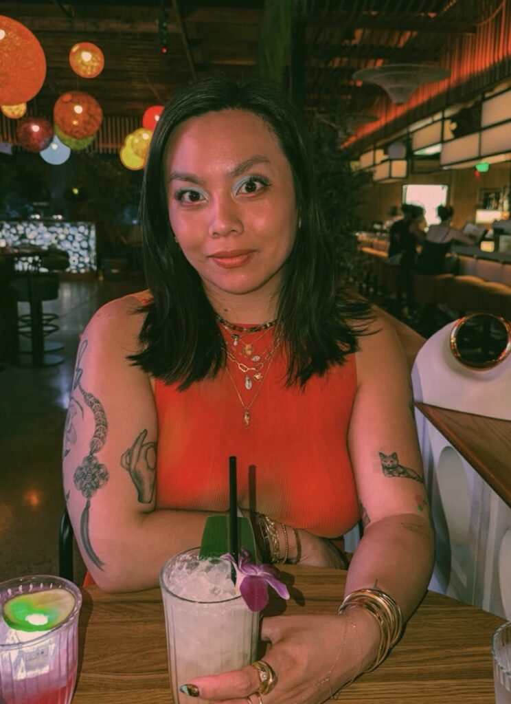 Sophia Chang sitting at a table in a restaurant with a cocktail on the table.