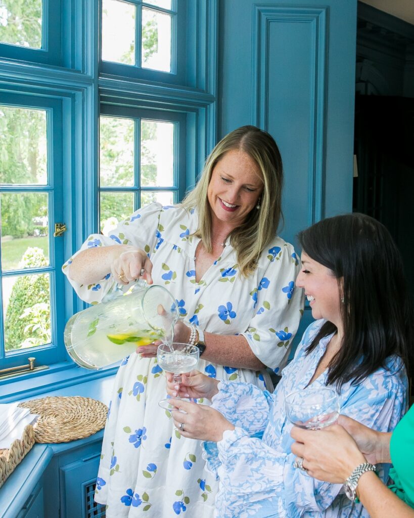Women pouring summer spritzers at a blue bay window bar setup during a Sewickley Mah Jongg party.